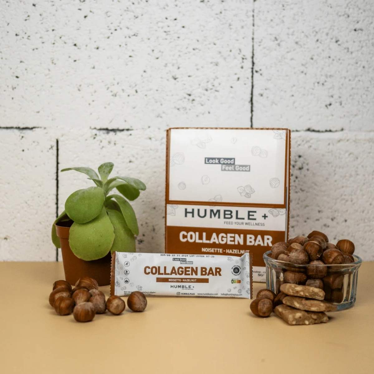 Barre protéines collagène noisette Humble avec packaging et noisettes sur fond beige