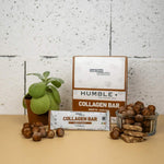 Barre protéines collagène noisette Humble avec packaging et noisettes sur fond beige
