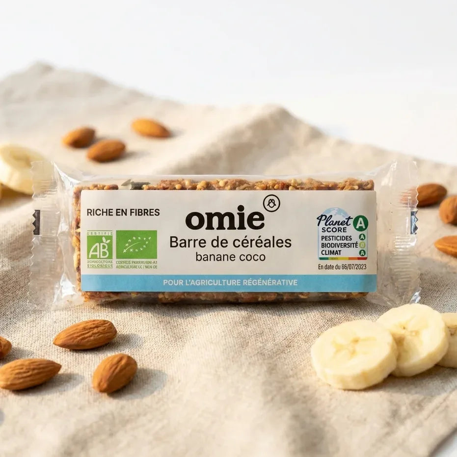 Barre céréales banane coco bio Omie 25g avec avoine et millet français sur fond blanc