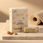 Barre protéinée amande Humble+ avec emballage crème et amandes sur surface marbre