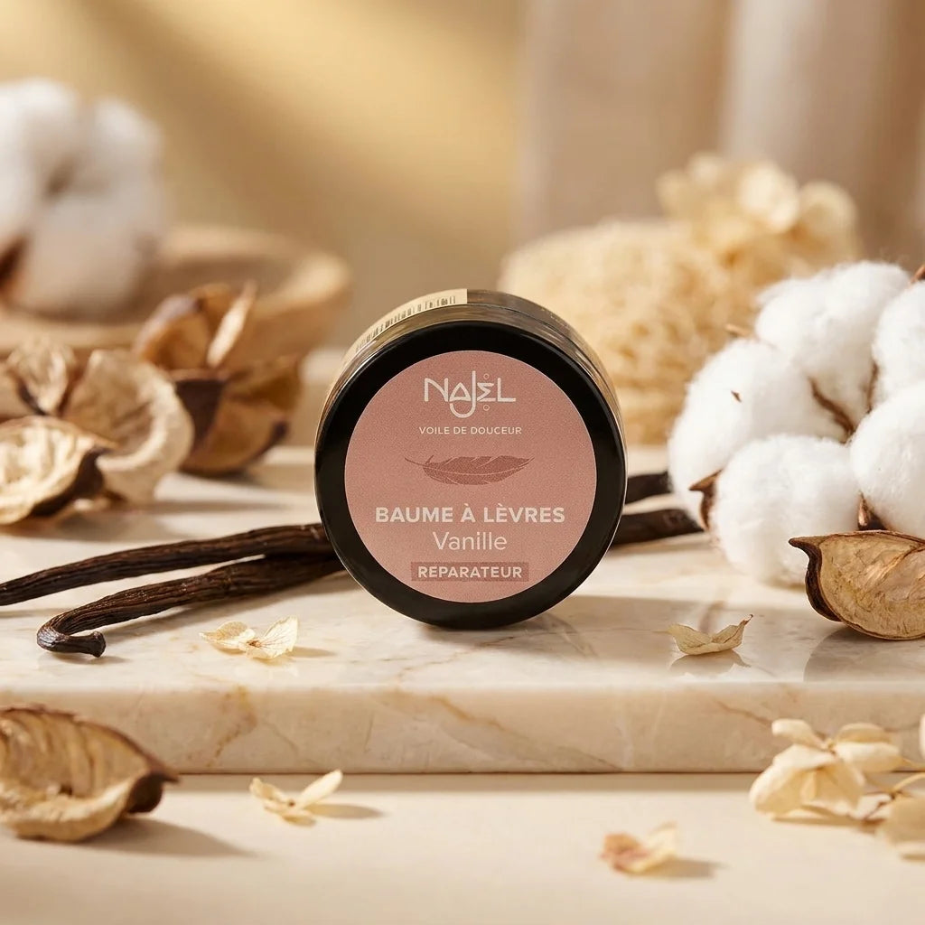 Baume à lèvres vanille bio Najel avec packaging noir et or rose sur surface marbre