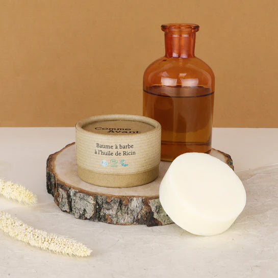 Un Baume à Barbe à l'Huile de Ricin Bio de la marque Comme Avant posé sur un rondin en bois