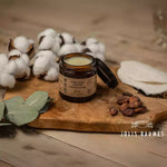 Baume naturel chouchou de la marque jolies baumes posé sur une planche en bois avec du coton et de l'eucalyptus