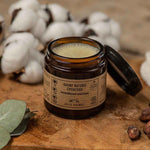 Un baume chouchou de la marque jolis baumes posé sur une table en bois rustique