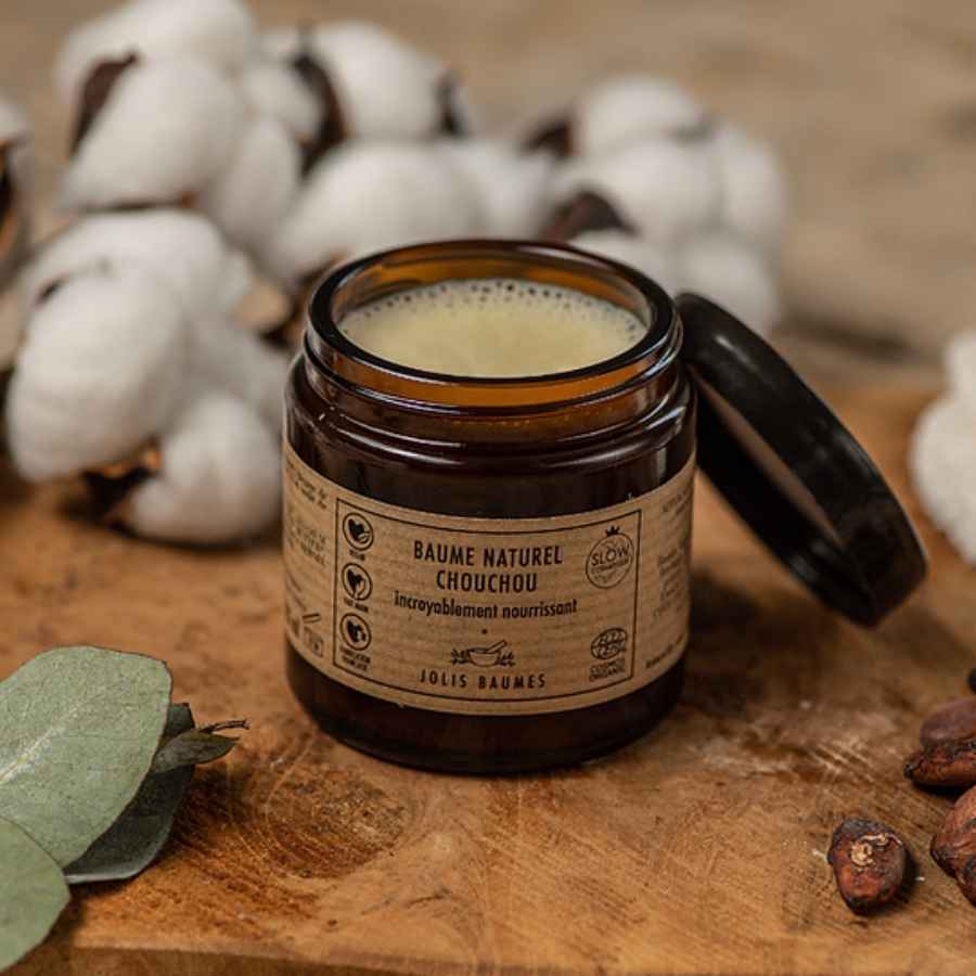 Un baume chouchou de la marque jolis baumes posé sur une table en bois rustique