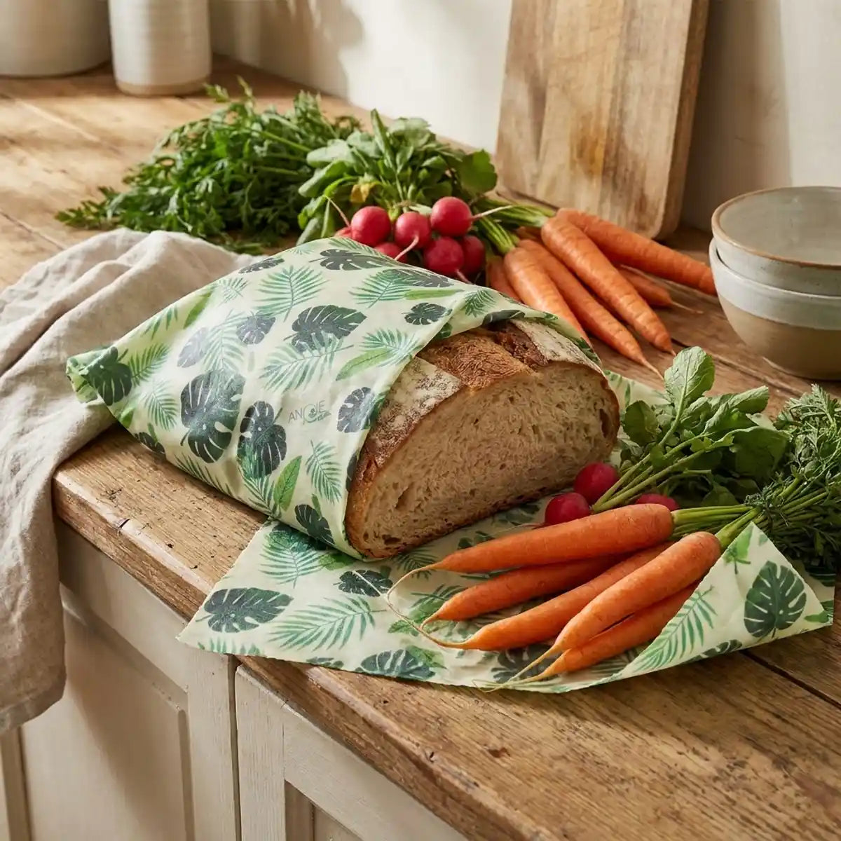 Bee wrap cire d'abeille taille L emballant légumes frais et pain sur plan de travail rustique