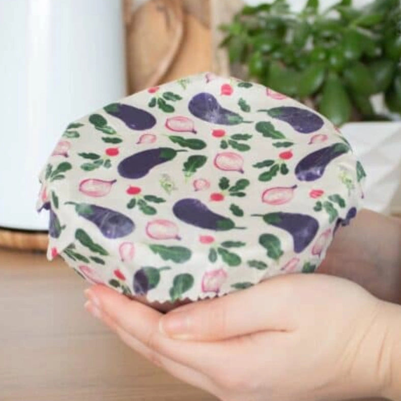 Zoom produit de la taille S de l'emballage à la cire d'abeille bee wrap de la marque Angie Be Green mis en situation sur un saladier et pris dans des mains