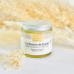 Un pot de beurre de Karité de 100 ml de la marque Comptoir des Huiles mis en scène sur une table avec des jolis fleurs