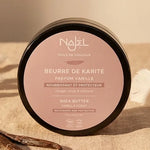 Beurre de Karité Vanille Najel 100g dans pot noir sur tissu beige avec gousses vanille