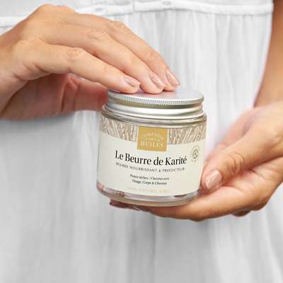 Un pot de beurre de Karité de 100 ml de la marque Comptoir des Huiles tenu en mains