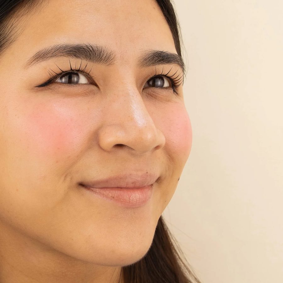Un blush crème rose appliqué sur les joues d'une femme