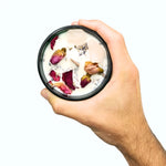 Bougie à la cire de soja fleurs séchées à la rose et quartz rose tenue dans une main.