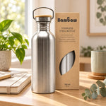 Bouteille en acier inoxydable 750 mL Bambaw avec bouchon en bambou, posée sur un bureau en chêne près d'un carnet et d'une plante verte