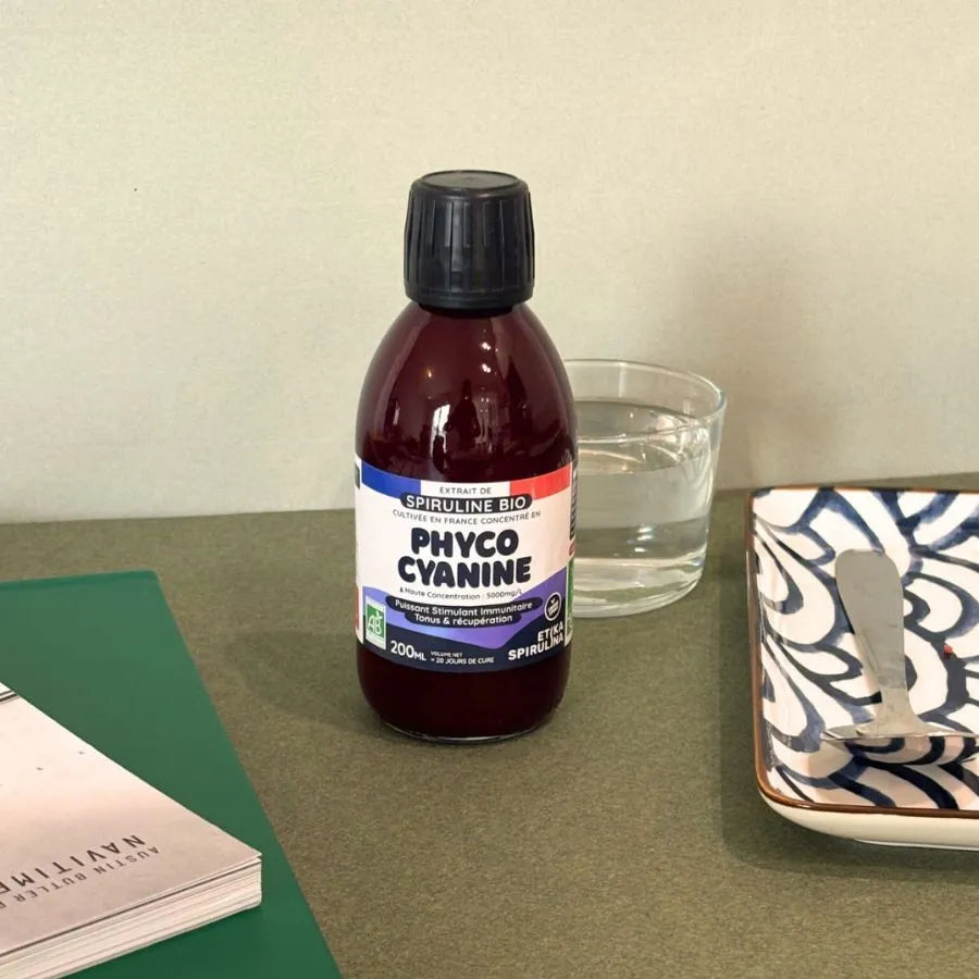 une bouteille de phycocyanine en 100 ml de la marque etika spirulina posée sur un bureau