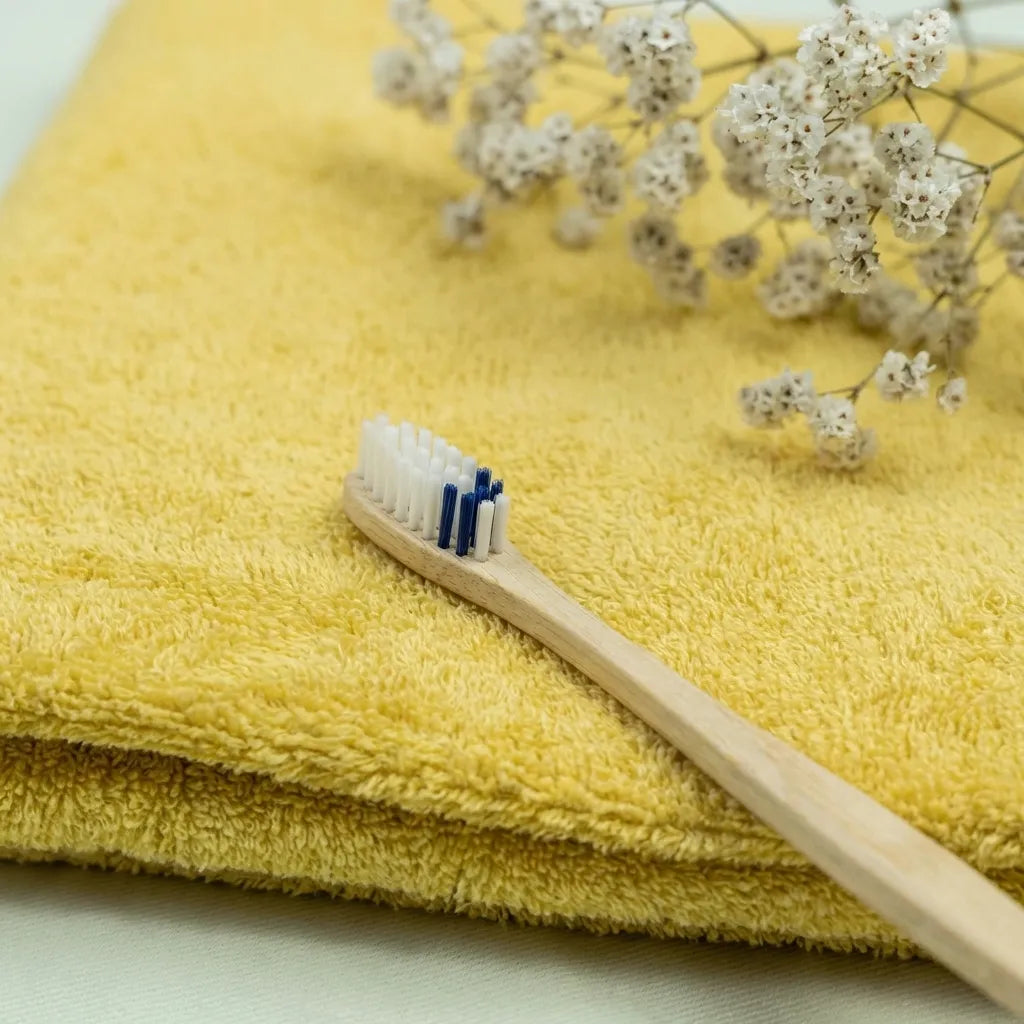 Brosse à dents en bois medium Apimani avec poils bleus sur fond jaune