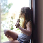 Une petite fille en tain de se brosser les cheveux avec une brosse en bambou de la marque cap bambou