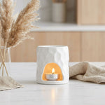 Brûle parfum céramique blanche sculptée avec bougie allumée sur marbre