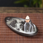 Un brûleur d'encens à reflux "Cascade de montagne" posé sur une table en paillage