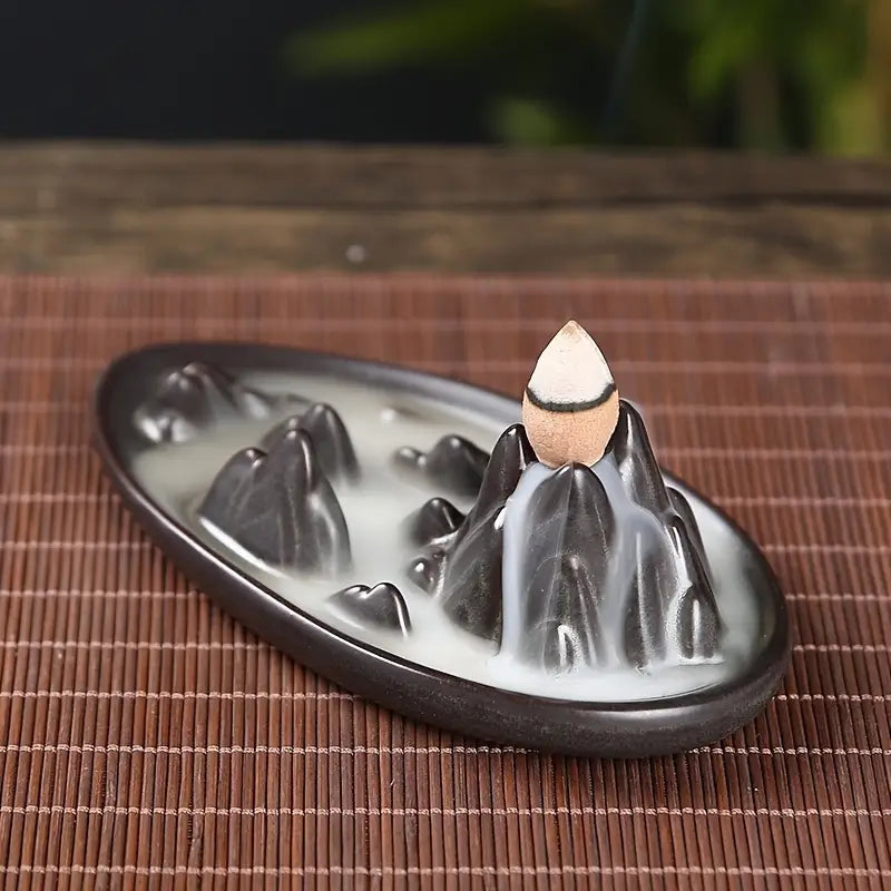 Un brûleur d'encens à reflux "Cascade de montagne" posé sur une table en paillage