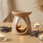 Brûleur céramique beige pour huiles essentielles avec lavande et bougies sur bois