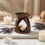 Brûleur de cire céramique chocolat avec huiles essentielles et bougies allumées sur marbre