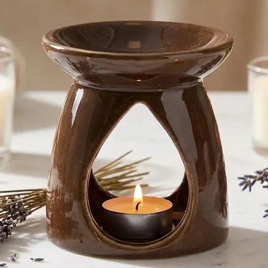 Brûleur de cire céramique chocolat avec huiles essentielles et bougies allumées sur marbre
