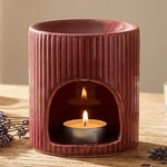 Brûleur de cire céramique rouge avec huiles essentielles et bougies dans un décor spa minimaliste