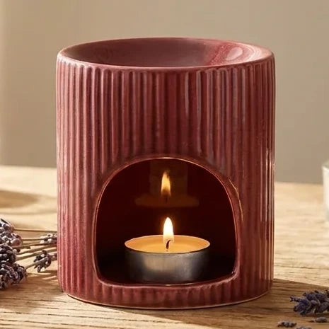 Brûleur de cire céramique rouge avec huiles essentielles et bougies dans un décor spa minimaliste
