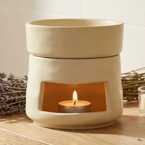Brûleur de cire céramique beige avec huiles essentielles sur étagère en bois, lavande et bougies