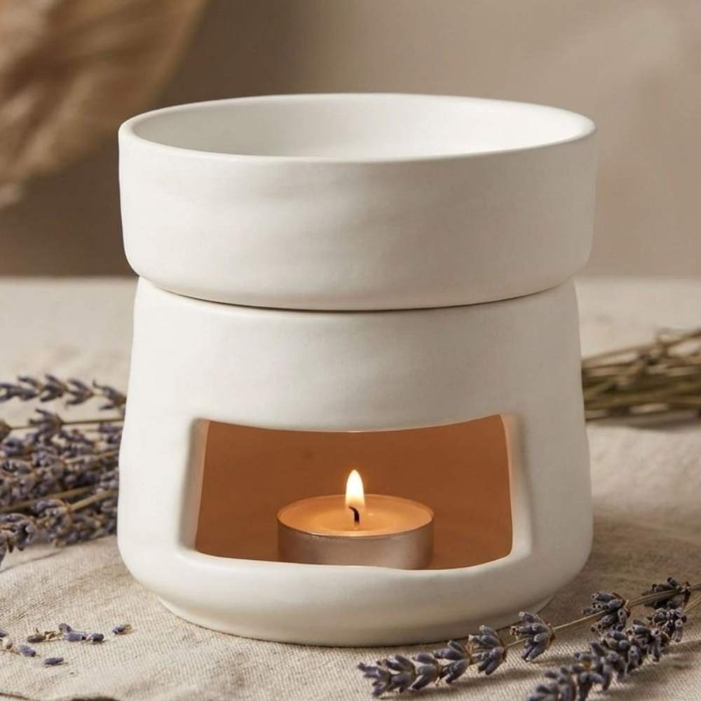 Brûleur de cire blanc en céramique avec une bougie chauffe-plat allumée