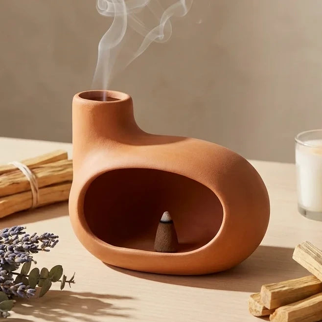 Brûleur d'encens céramique maison orange avec palo santo et bougies allumées