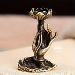 Un brûleur d'encens en cascade en forme de main de Bouddha avec une fleur de lotus, posé sur une surface.