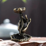 Un brûleur d'encens en cascade en forme de main de Bouddha avec une fleur de lotus, en gros plan.
