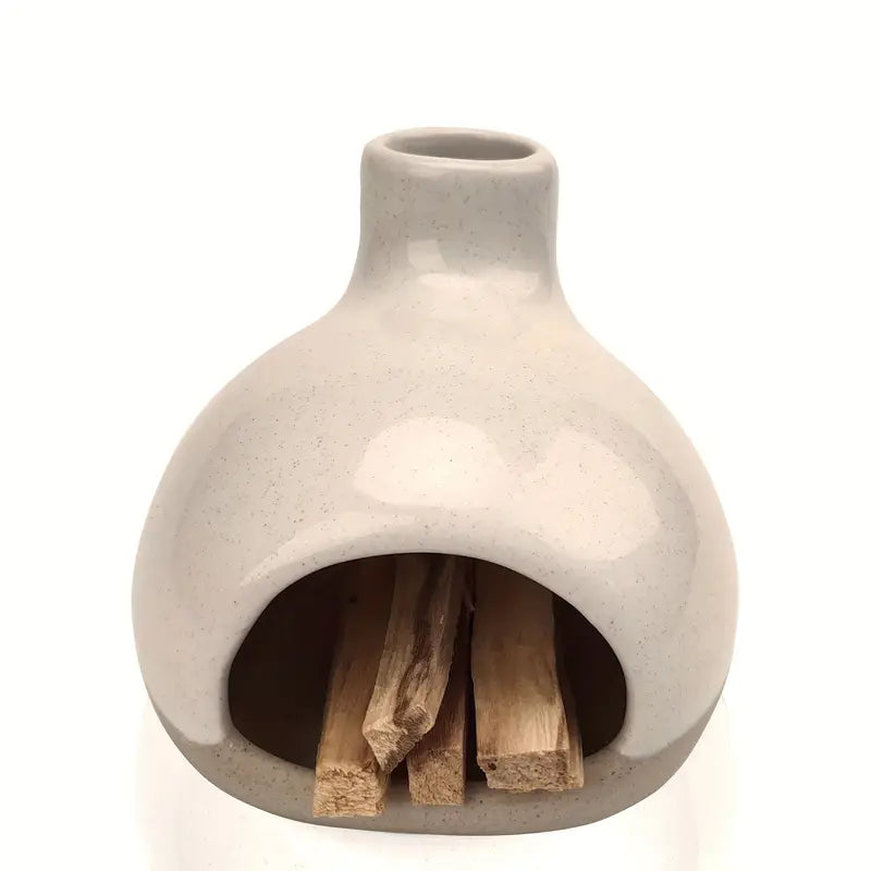 Un brûleur d'encens en céramique avec collecteur de cendres avec trois bâtonnets de palo santo dedans