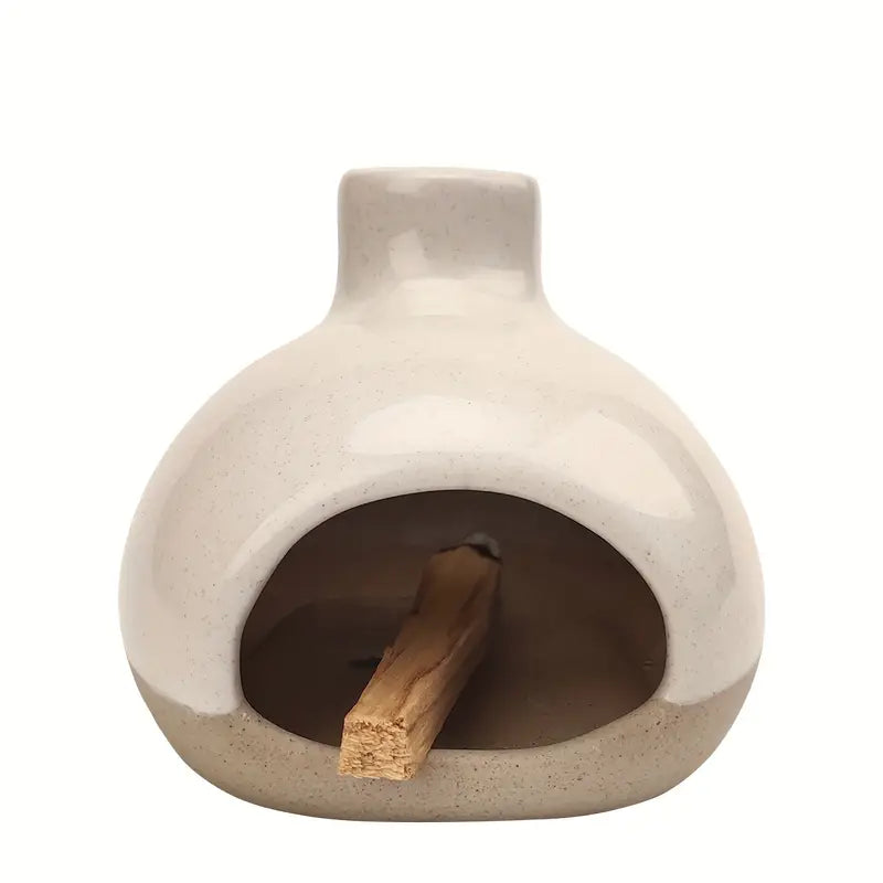 Un brûleur d'encens en céramique avec collecteur de cendres avec un bâtonnet de palo santo à l'intérieur