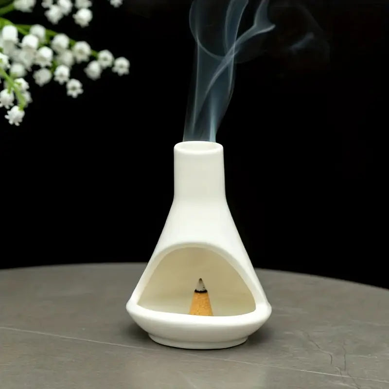 Un Brûleur d'Encens en Porcelaine Blanc avec un cône d'encens en train de bruler dedans