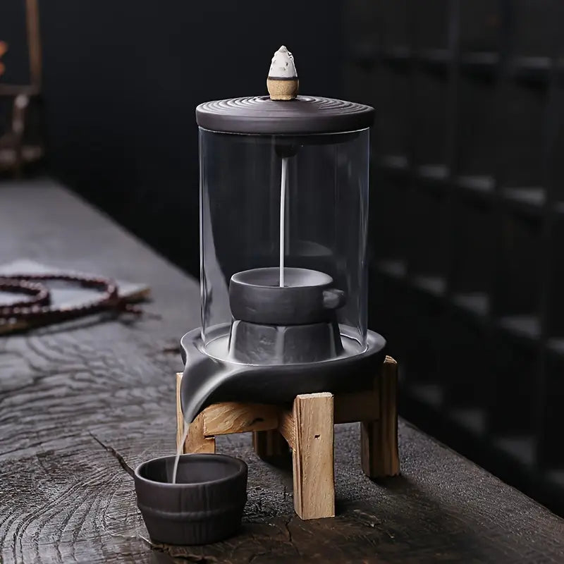 Un Brûleur d’encens à reflux en céramique & verre avec support bois sur une table en bois