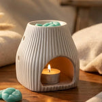 Brûleur Scentchips Flare Désert blanc avec fondants turquoise et bougie allumée sur bois