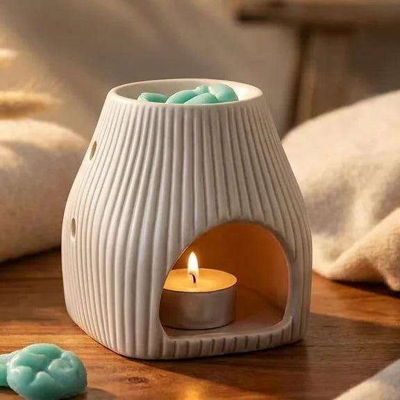 Brûleur Scentchips Flare Désert blanc avec fondants turquoise et bougie allumée sur bois