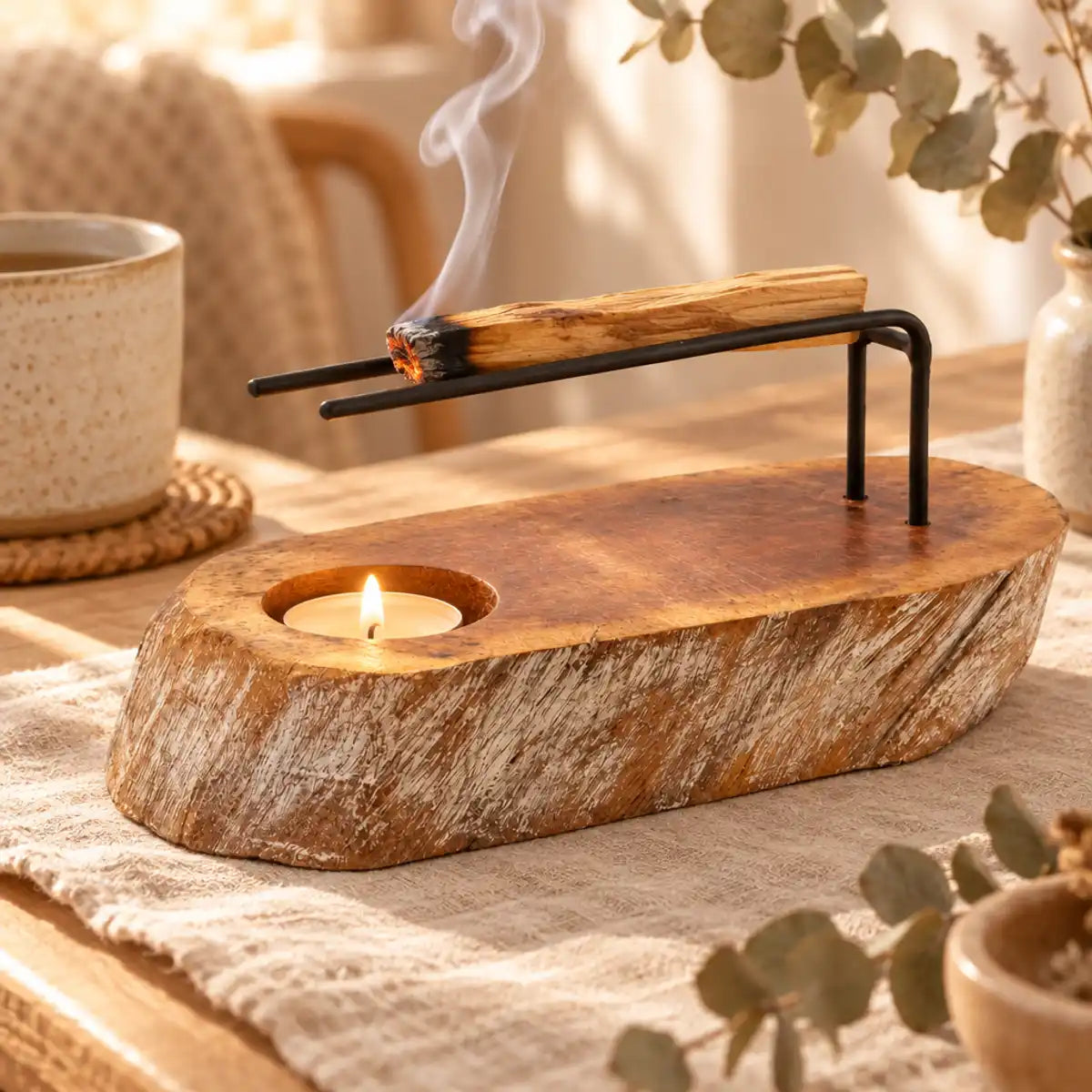 Brûleur palo santo en bois de gamal blanchi, bâton fumant sur des tiges métalliques, bougie chauffe-plat et eucalyptus séché sur table en chêne