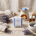 Un paquet de quatre carrés fondants Drake à la senteur Lavande sur une table en bois devant un brule parfum