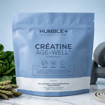 Humble+ Créatine Age-Well 300g sur surface marbre avec légumes verts et équipement fitness