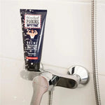 Un tube de Crème dépilatoire douche Blondépil Homme posé sur un pommeau de douche