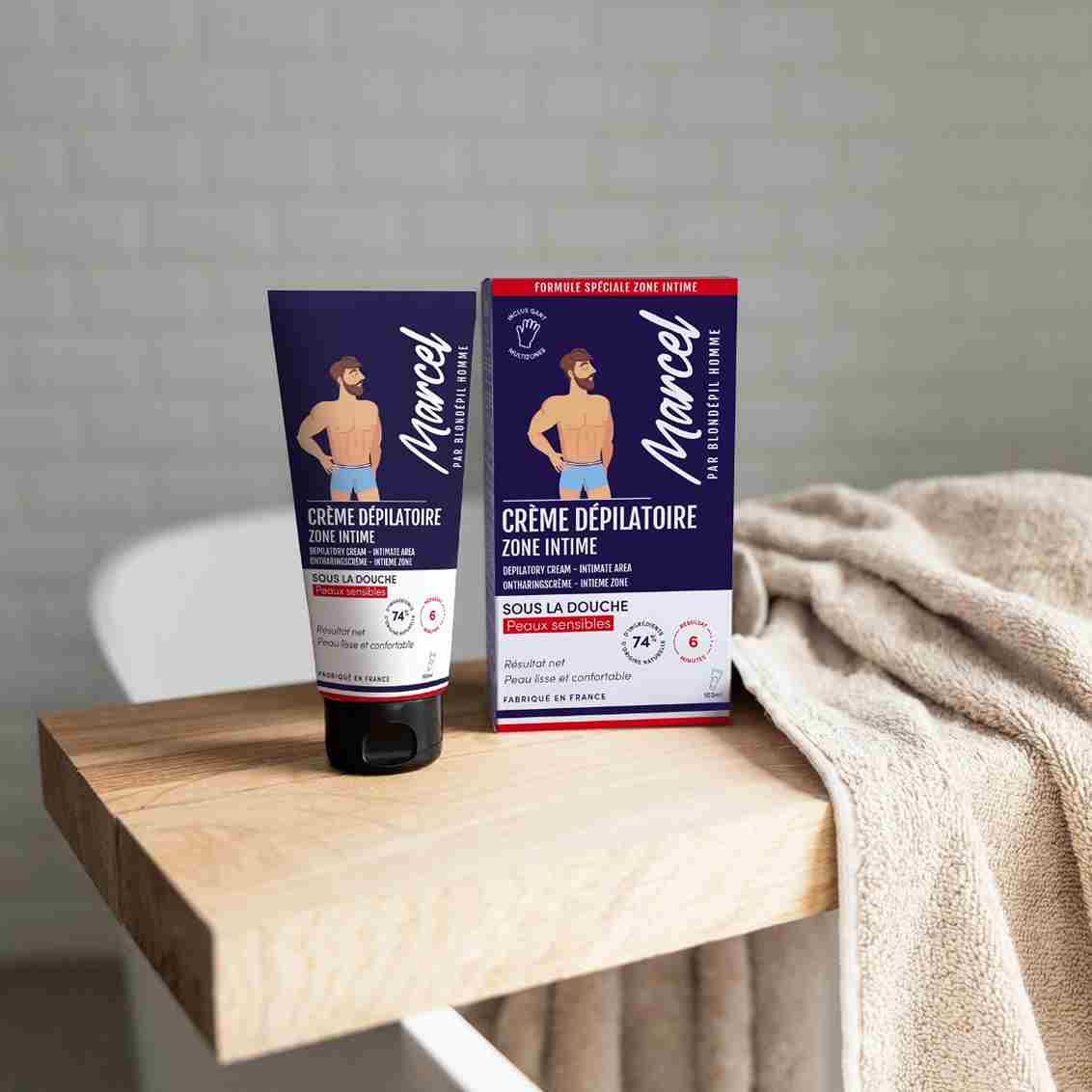 Un tube de crème dépilatoire zone intome de la marque marcel par blondepil posé sur une planche de bois 