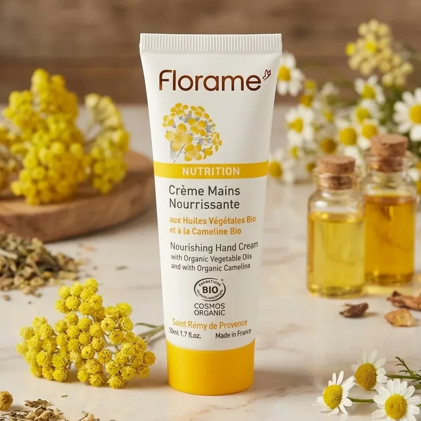 Crème mains nourrissante bio Florame 50ml sur surface marbre avec fleurs jaunes et ingrédients naturels