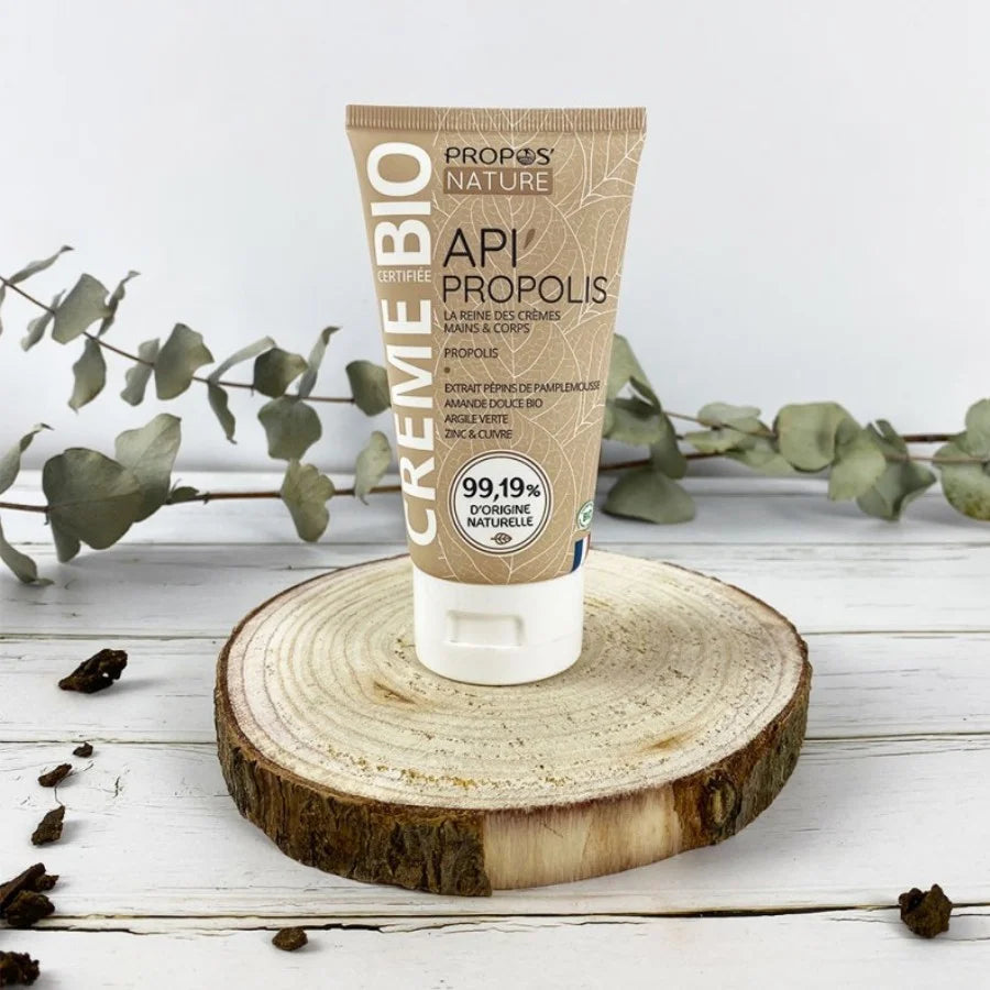 Photo d'ambiance d'Un tube de crème Propolis bio de 100 ml de la marque Propos’Nature posé sur une rondin de bois