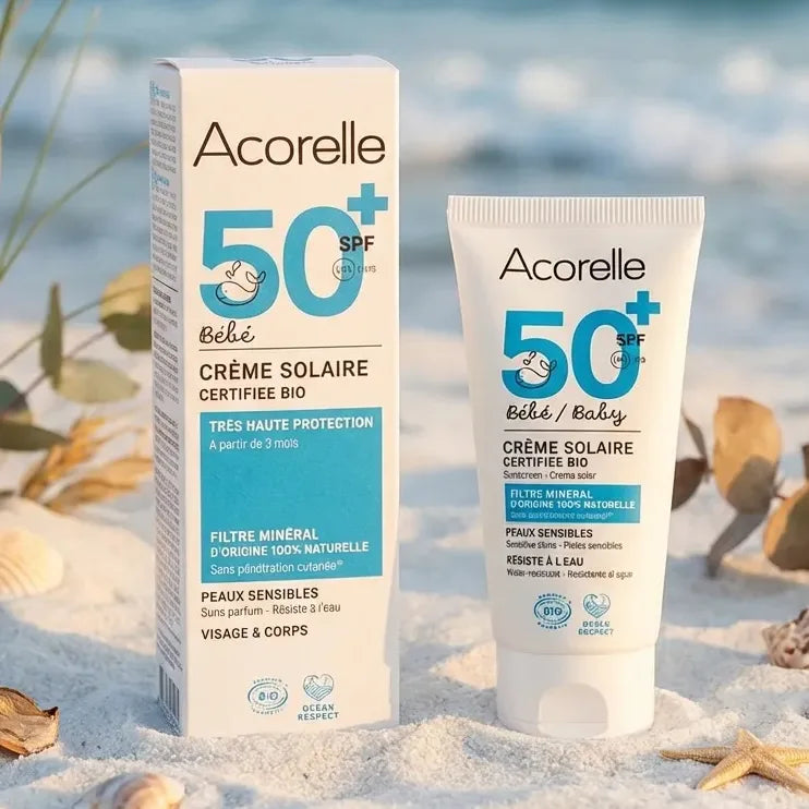 Crème solaire bébé SPF 50 bio Acorelle 50ml sur plage avec coquillages