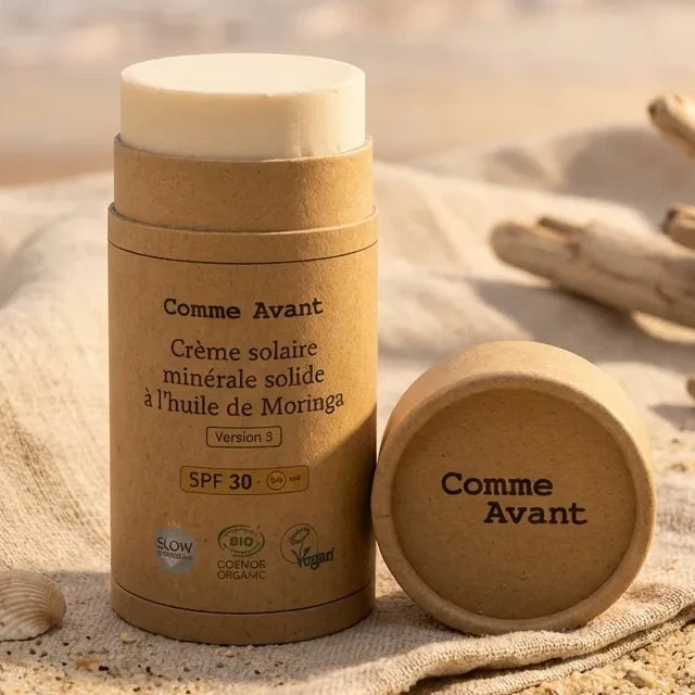Crème solaire minérale solide SPF30 Comme Avant dans son emballage écologique sur plage