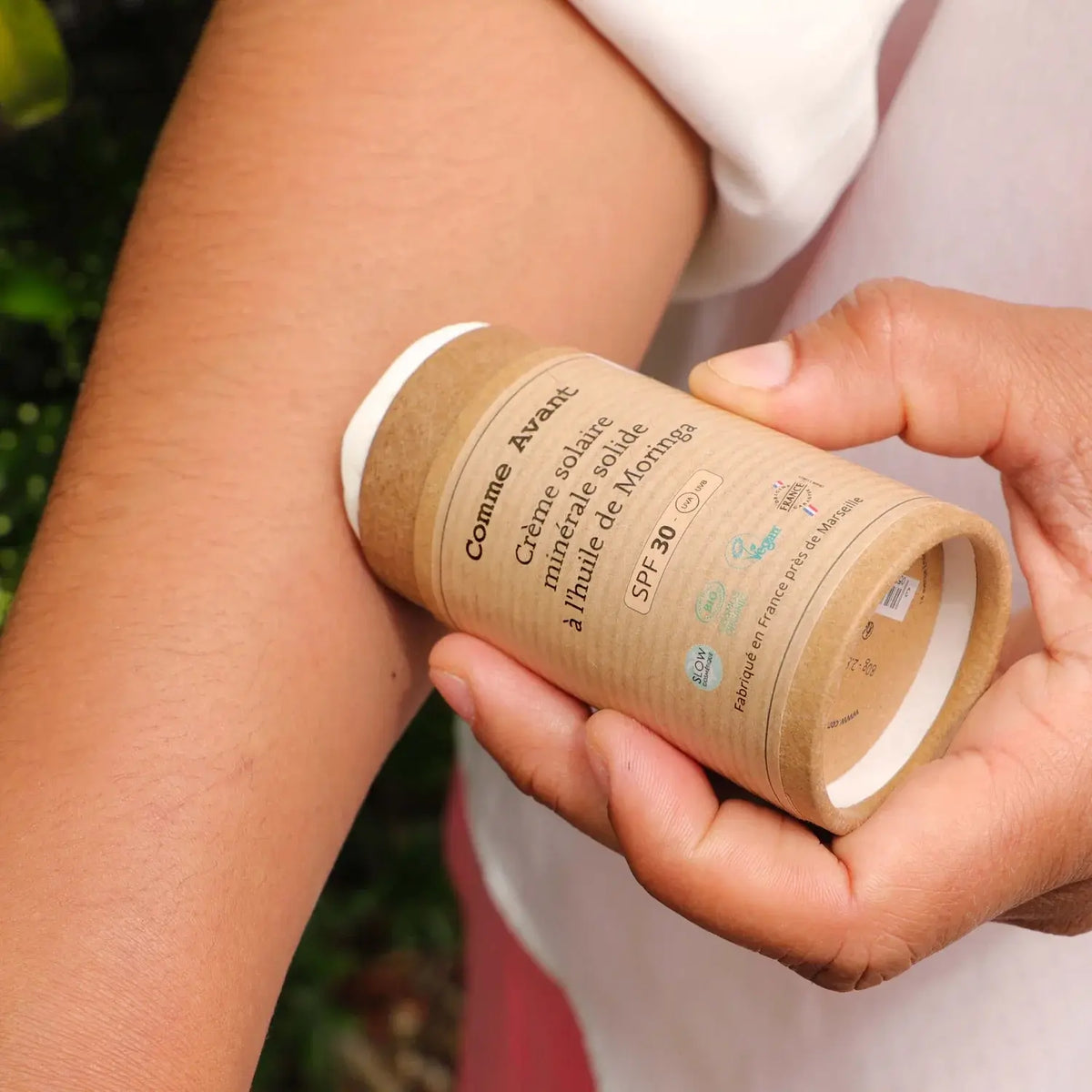 Zoom sur une personne en train d'appliquer sur son bras de la crème solaire minérale solide Comme Avant