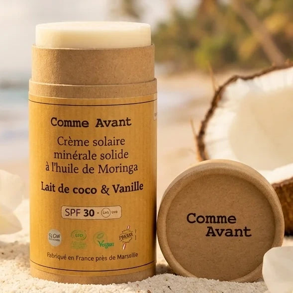 Crème solaire minérale solide SPF30 Comme Avant à la vanille et lait de coco sur fond de plage
